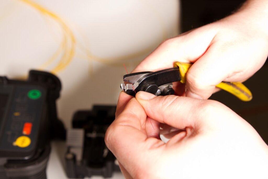 LWL Werkzeug in Nahaufnahme beim Schneiden einer Glasfaser mit Spezialzange zur Vorbereitung auf das Spleissen